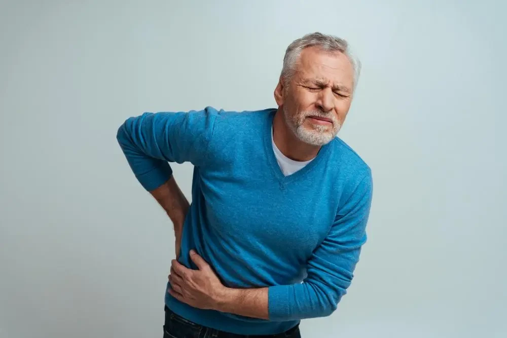 Older man holding his lower back due to kidney pain